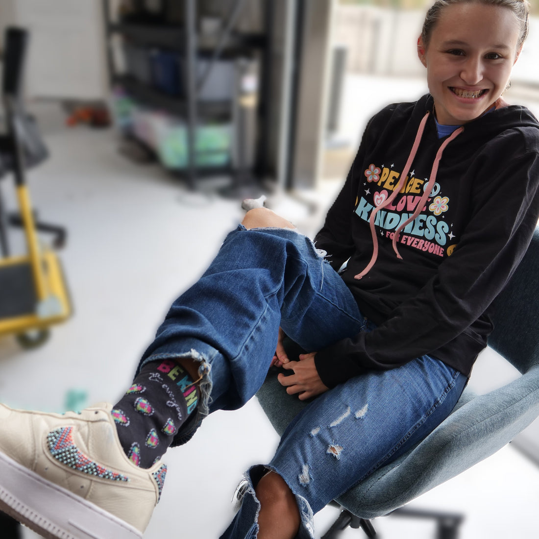 Jordyn, in the shirt shop, modeling our Be Kind to Everyone® mid-calf woven socks.
