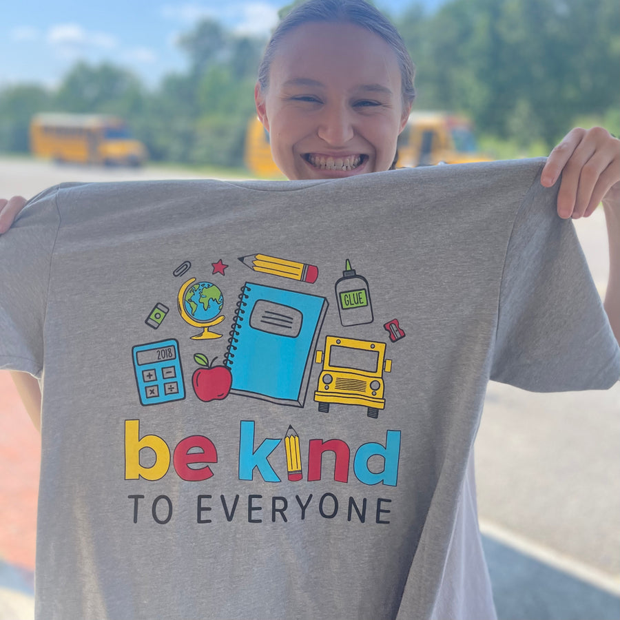 Jordyn, holding up our NEW School Be Kind to Everyone® short-sleeved tee.