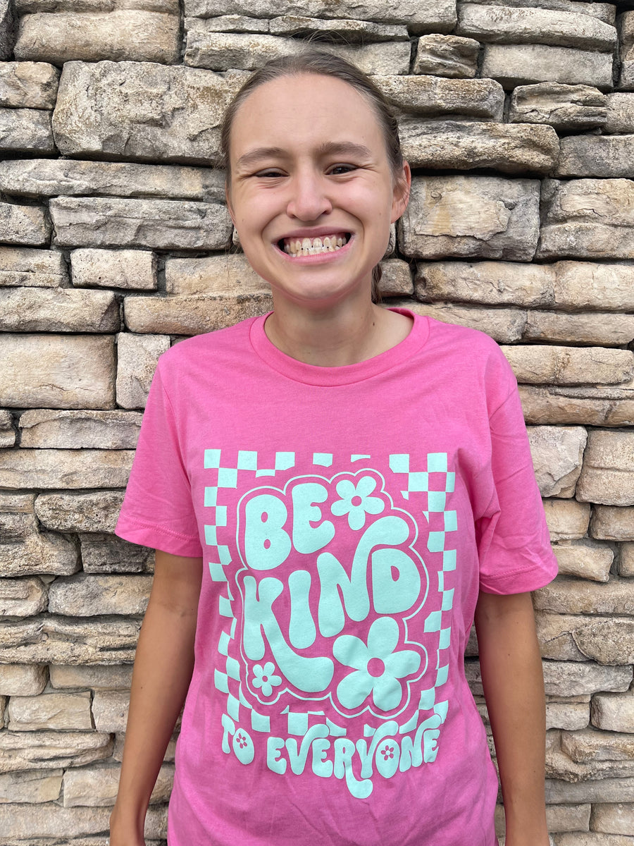 Jordyn wearing a small in our Adult Pink Retro Checkerboard Be Kind to Everyone® Tee.