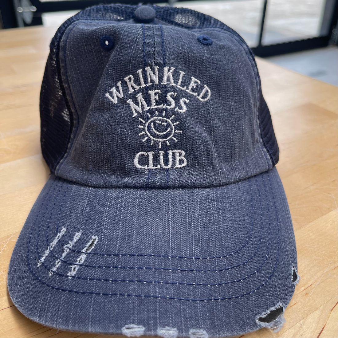 Wrinkled Mess Club Hat: Distressed for a vintage look, this navy blue hat is embroidered with Wrinkled Mess Club on the front and Be Kind to Everyone® with Jordyn&