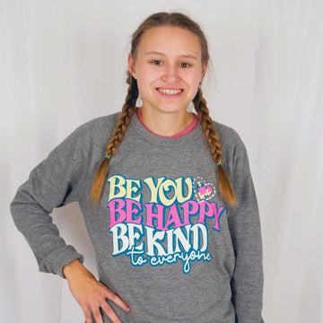Jordyn modeling a small in our Be You, Be Happy, Be Kind to Everyone® crewneck sweatshirt.