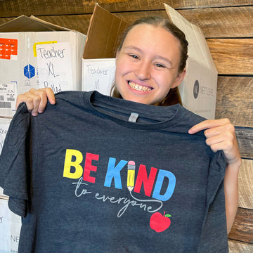 Jordyn holding up our "Teacher" Be Kind to Everyone® short-sleeve shirt.